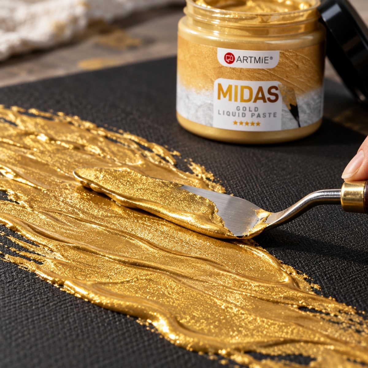 Nanošenje zlatne metalik paste ARTMIE MIDAS špahtlom na crno platno — makro